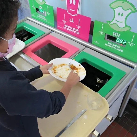 Élève déposant ses déchets alimentaires dans la table de tri TRIGO